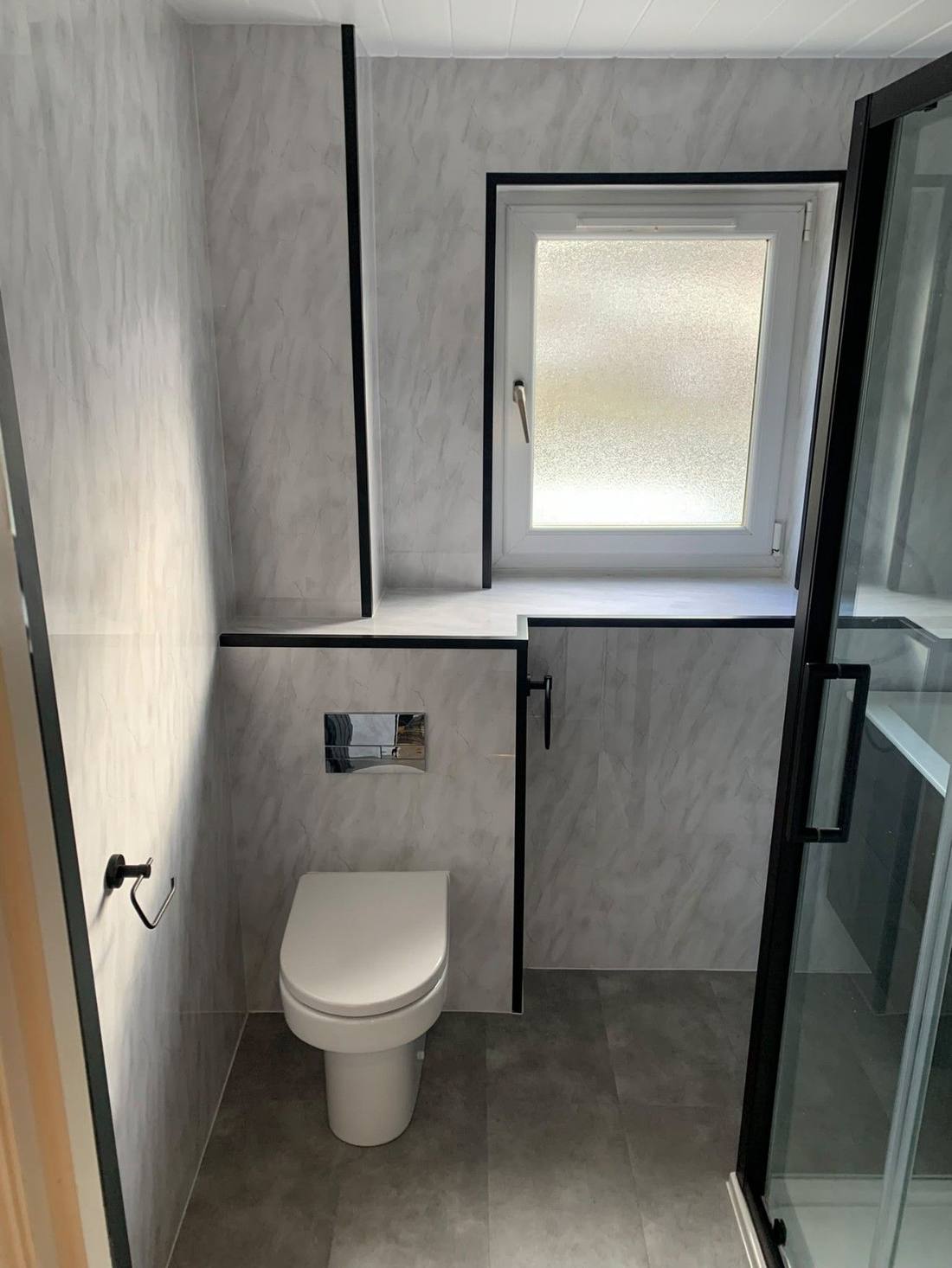 Toilet and shower enclosure finished with panelling and tiling