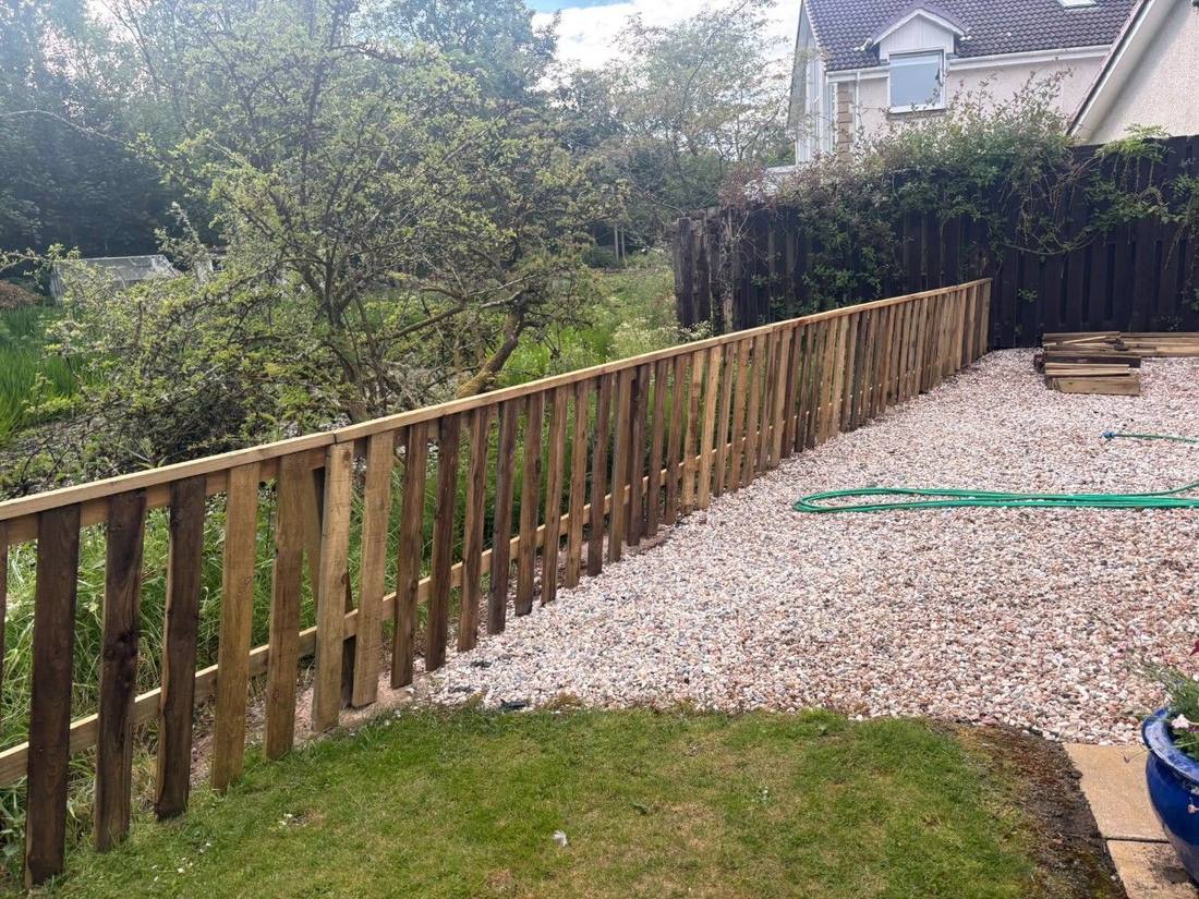 Newly built timber fence running along a sloped garden boundary