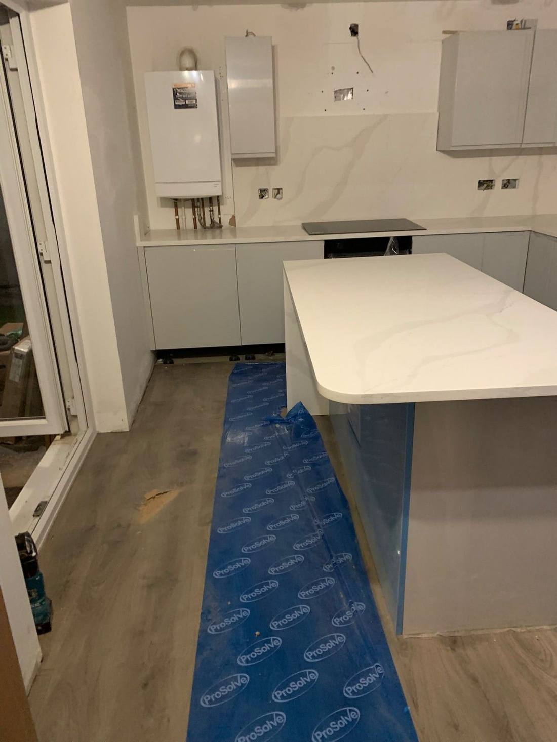 Kitchen island with quartz worktop, boiler and wall units fitted around it